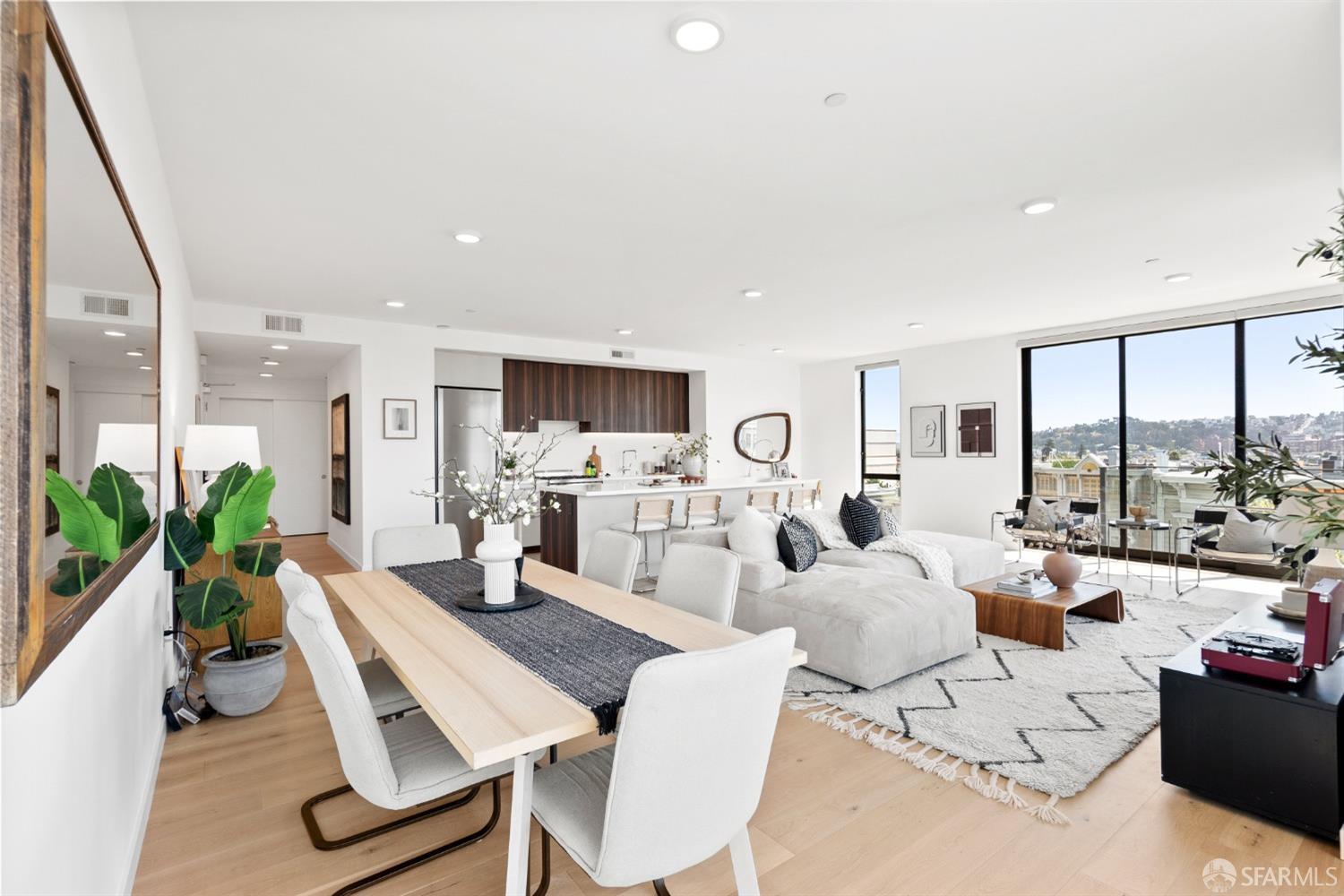 a living room with furniture large windows and view of kitchen