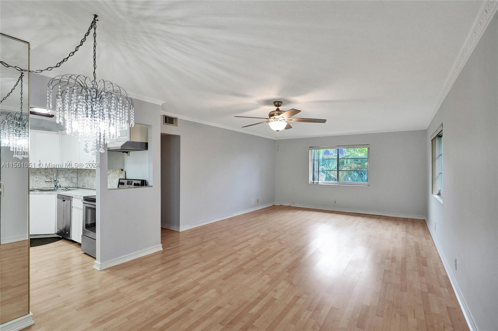 a view of a room with a kitchen island wooden floor and stainless steel appliances