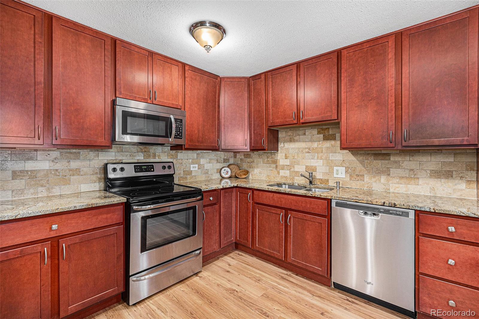 a kitchen with granite countertop wooden cabinets stainless steel appliances and a sink