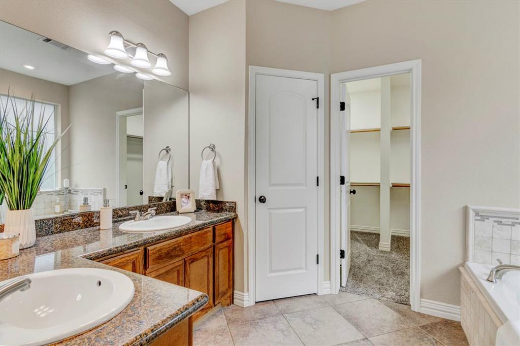 a bathroom with a sink double vanity granite tub shower and a mirror