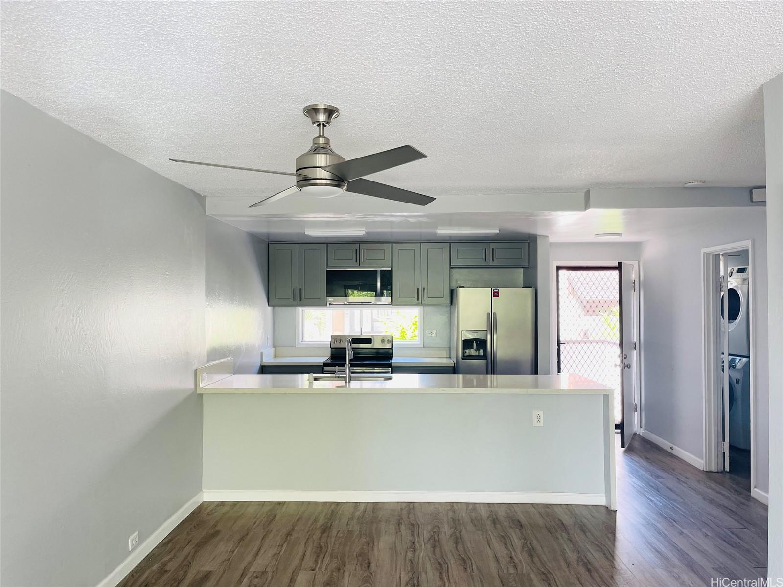 a view of a kitchen with kitchen island a sink wooden floor and counter top space