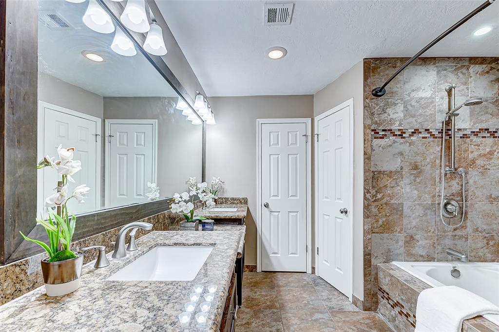 a bathroom with a granite countertop tub sink and mirror