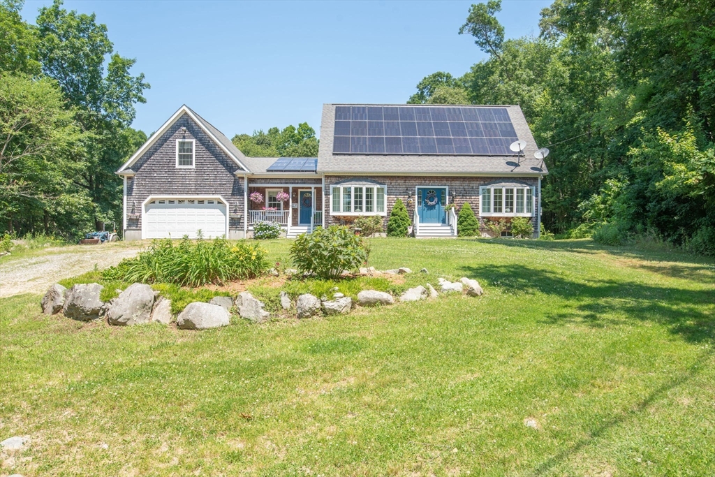 a view of a house with a big yard plants and large trees