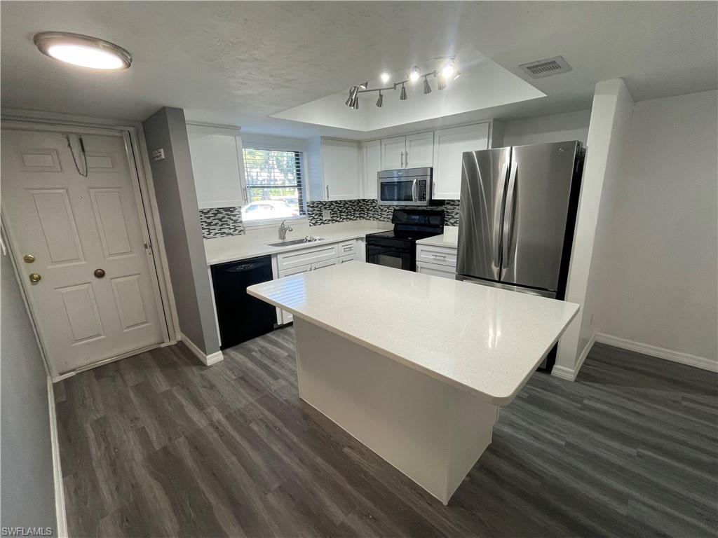 a large white kitchen with wooden floor