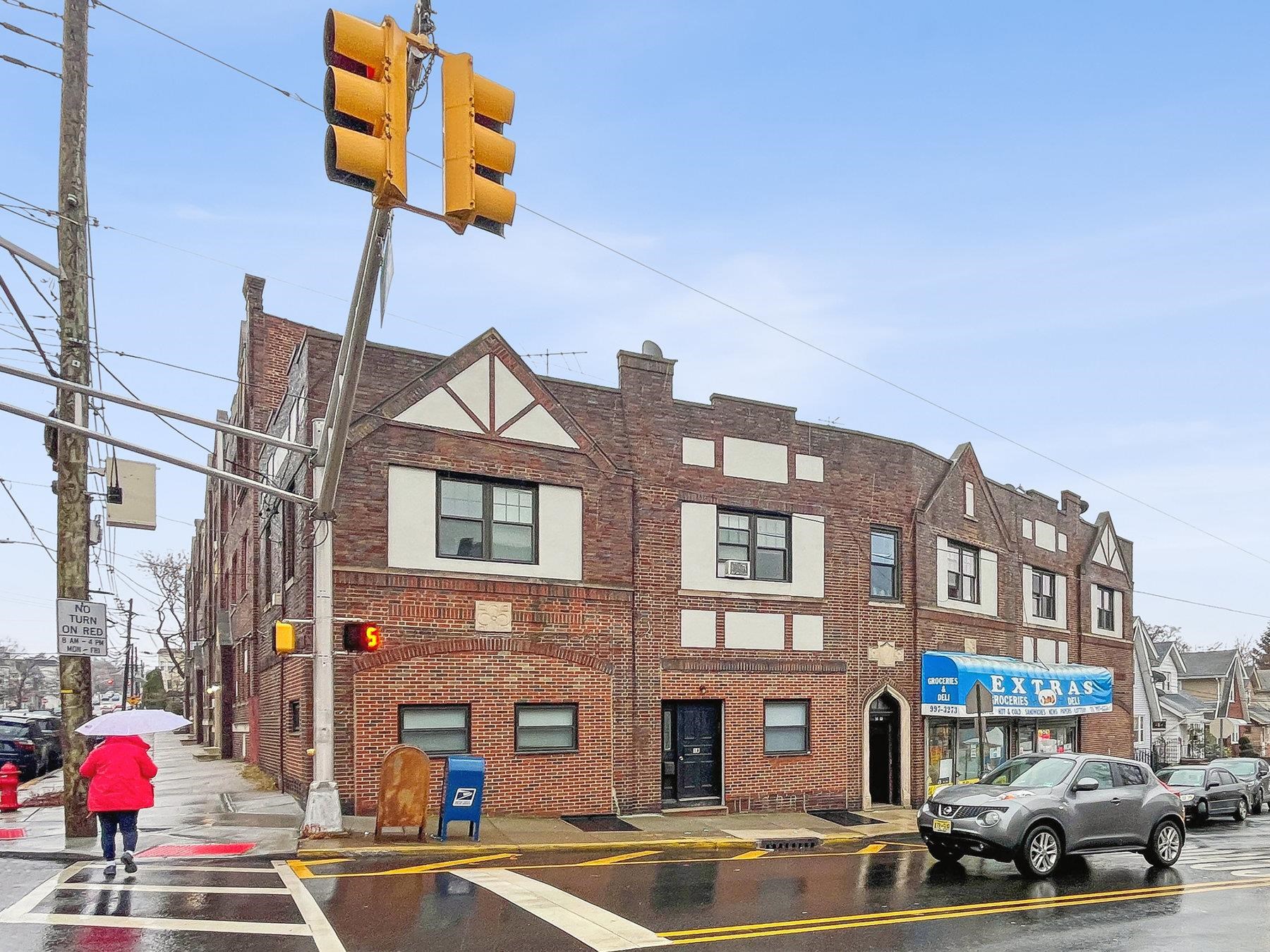 a front view of a building with lot of cars and trees