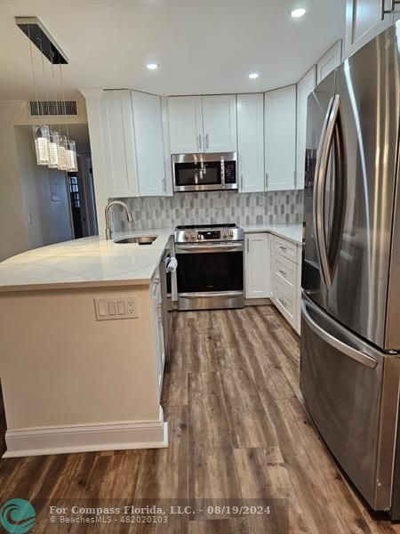 a kitchen with stainless steel appliances a refrigerator sink and microwave