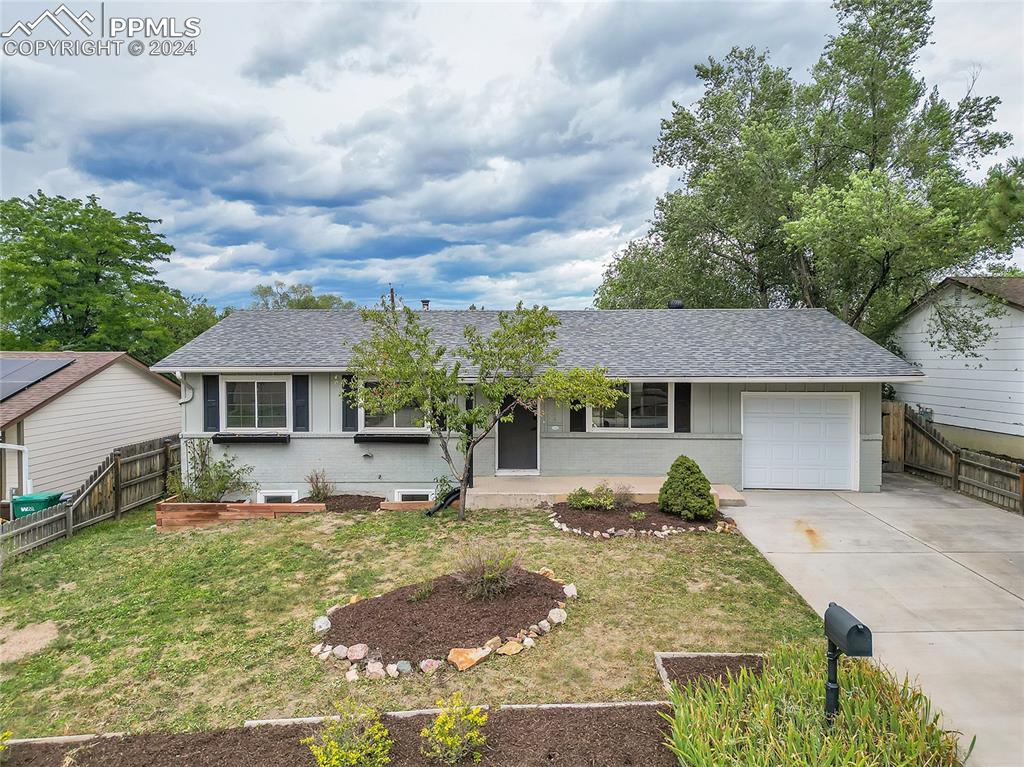 Ranch-style house featuring a garage and a front lawn