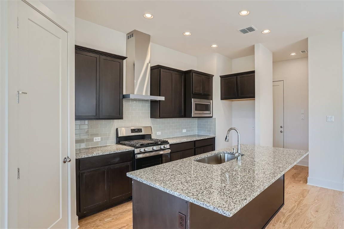 a kitchen with stainless steel appliances granite countertop a sink stove and refrigerator