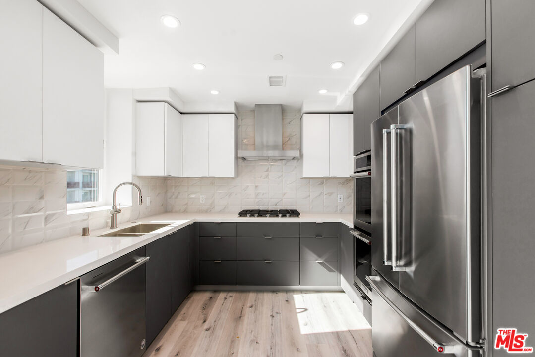 a kitchen with a sink a counter top space stainless steel appliances and cabinets