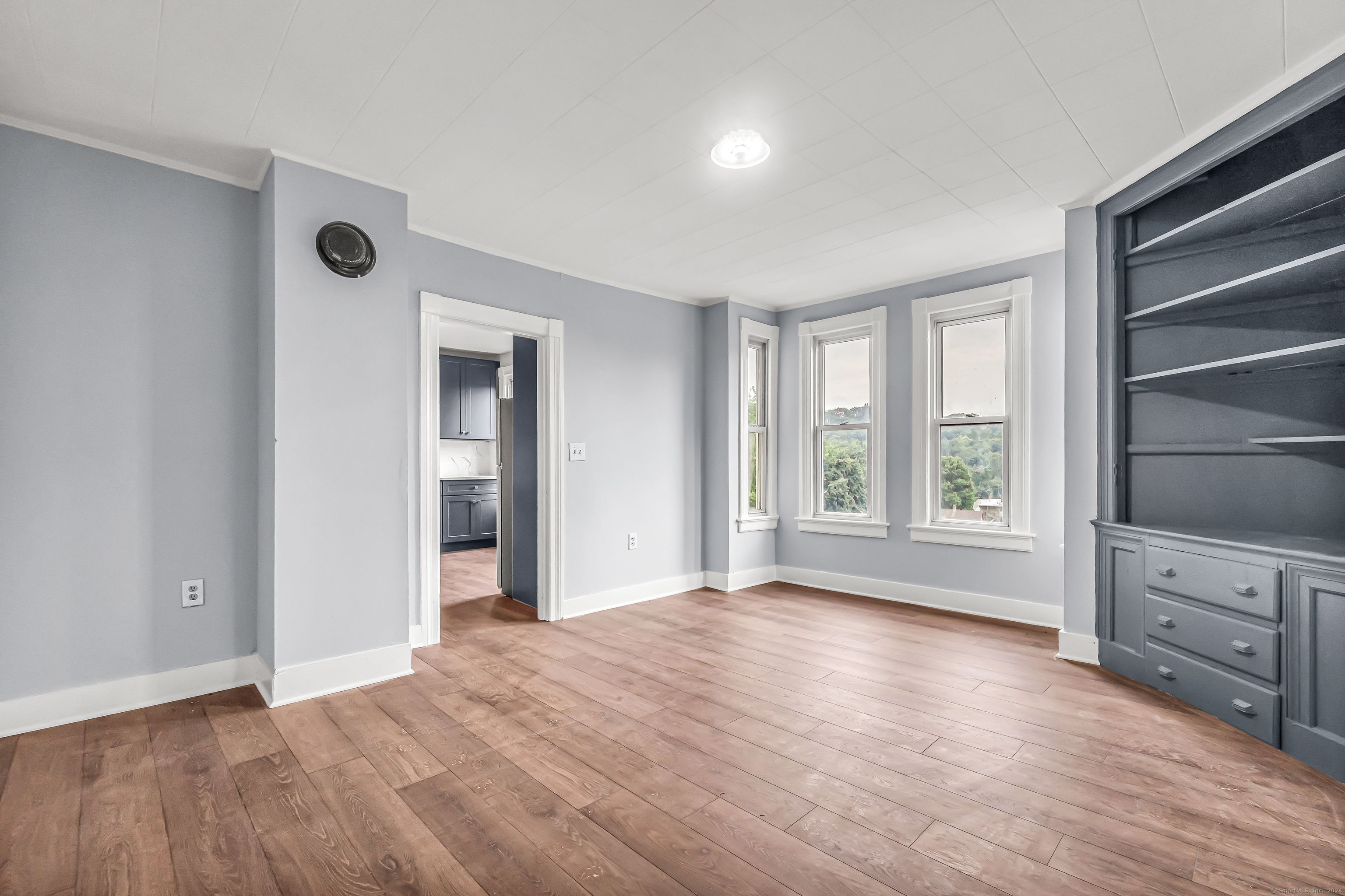 a view of an empty room with a window and wooden floor