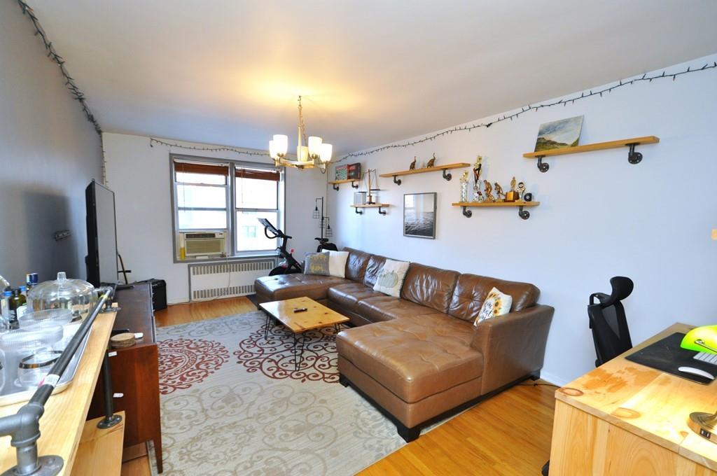 Living room featuring radiator heating unit, hardwood flooring and a notable chandelier