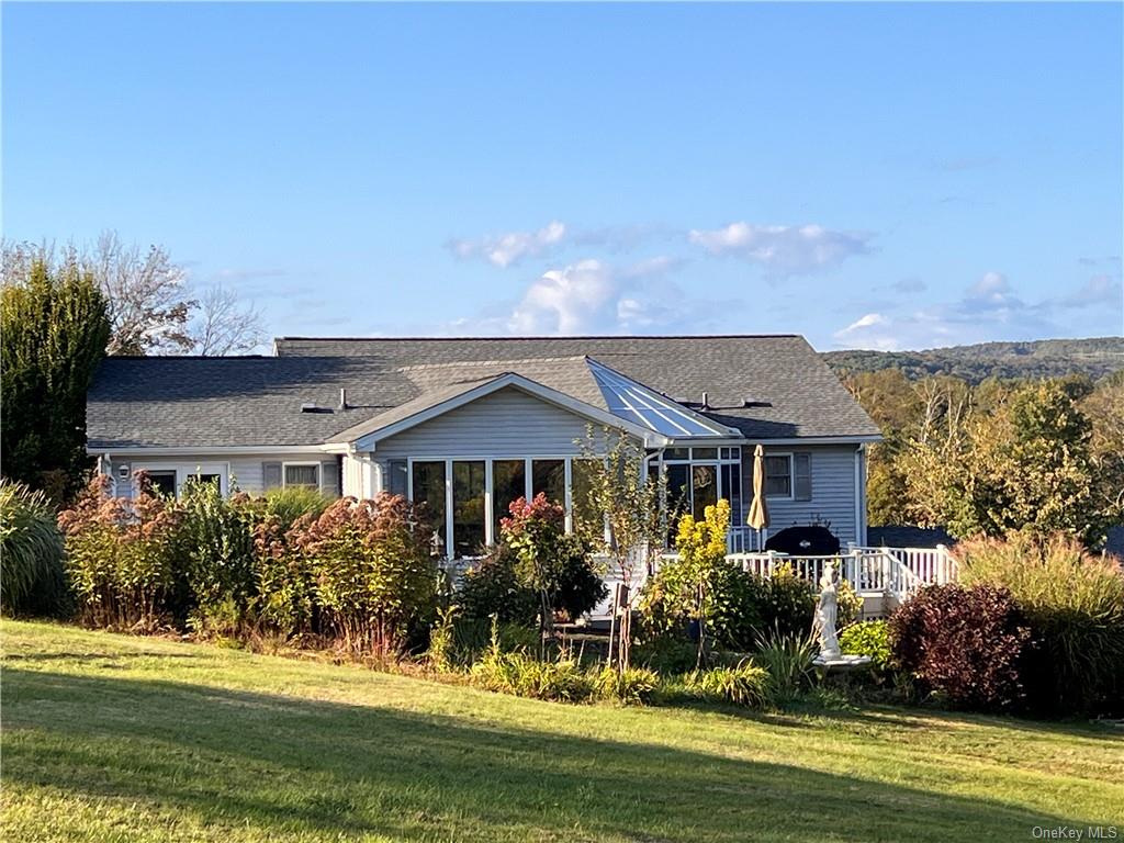 Rear view of house featuring a wooden deck and a yard