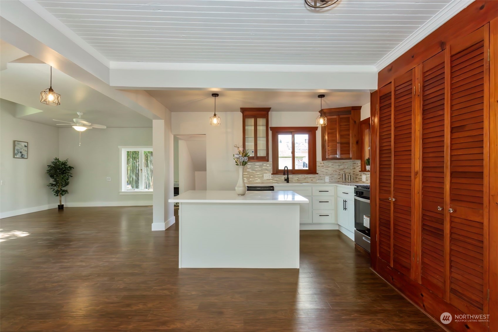 a view of a kitchen with kitchen island a sink wooden floor and a living room