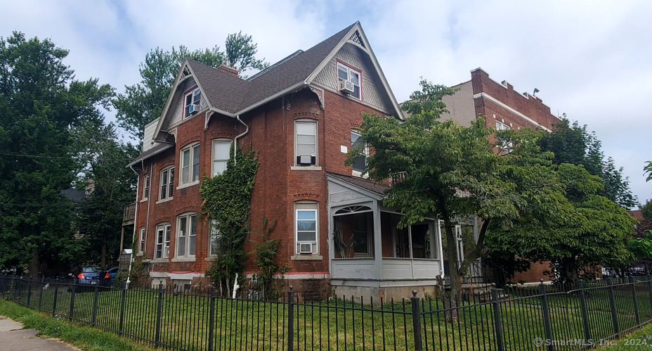 a view of a yard in front of a brick house with large windows