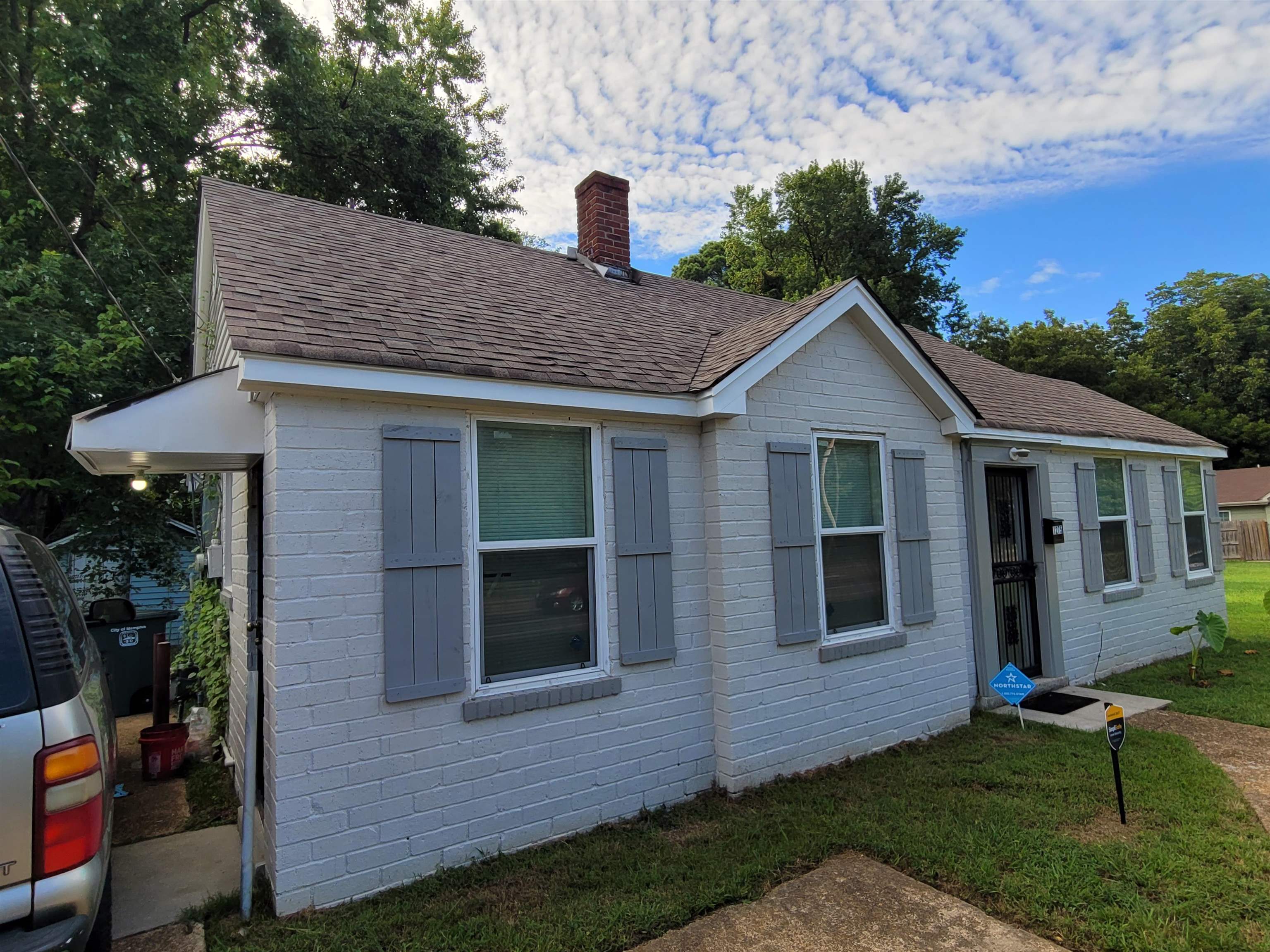 a view of a house with a yard potted plants and a table