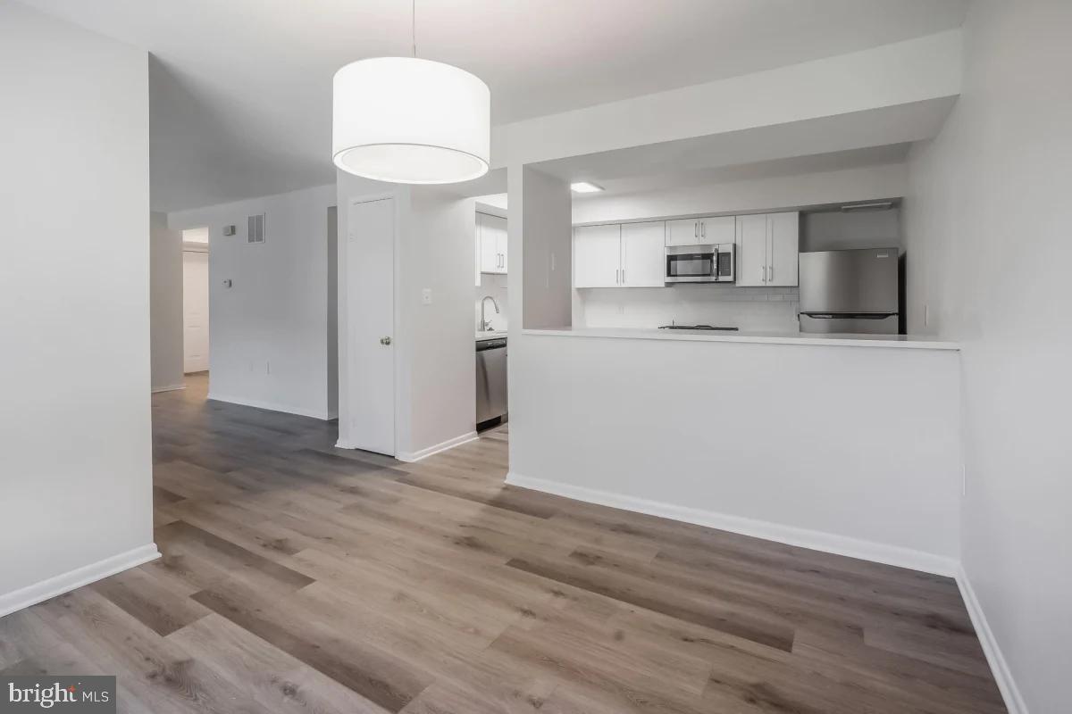 a view of kitchen and empty room with wooden floor