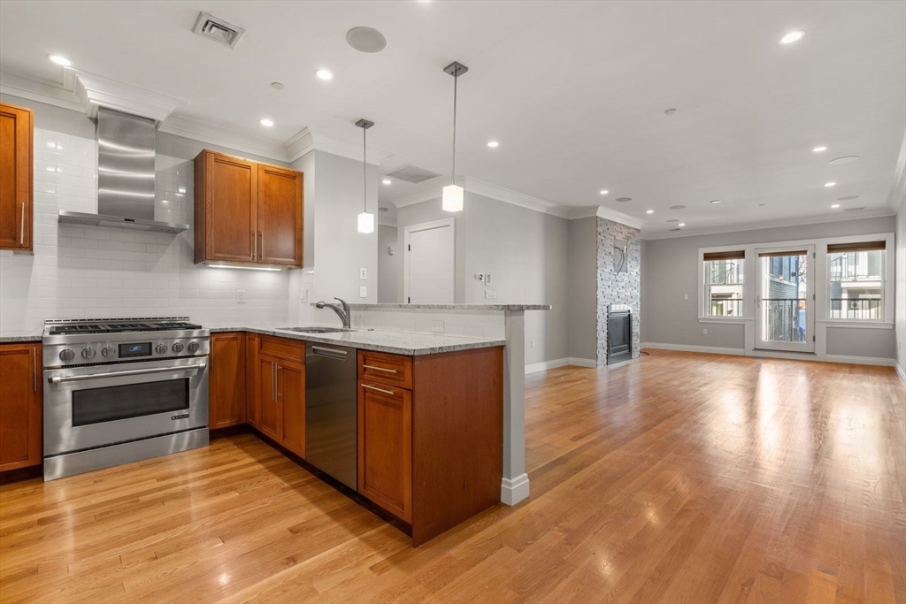 a large kitchen with stainless steel appliances granite countertop a stove and a wooden floors