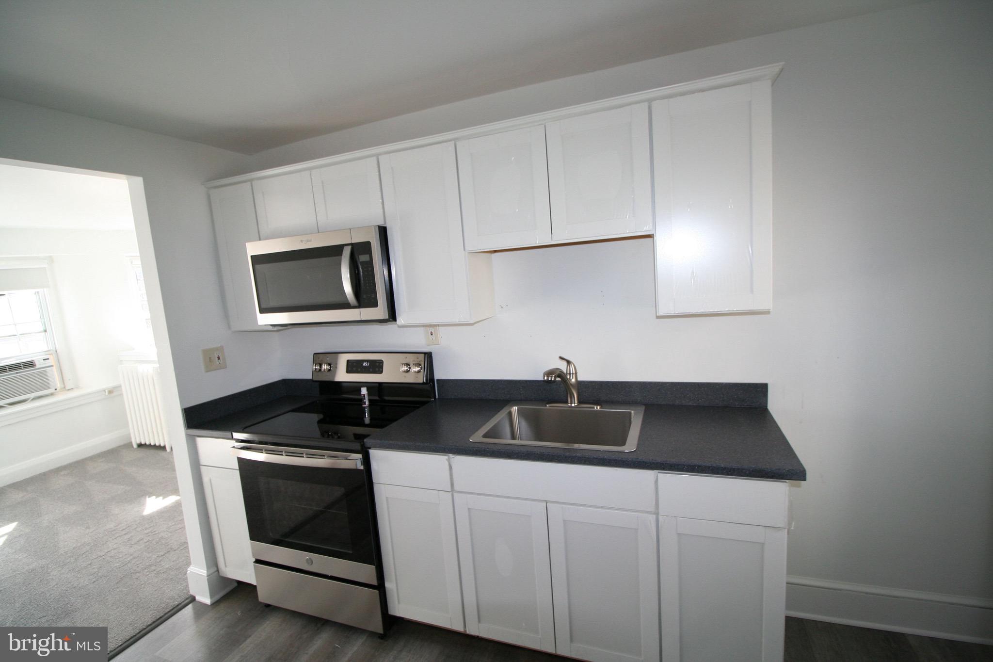 a kitchen with sink a microwave a stove and cabinets