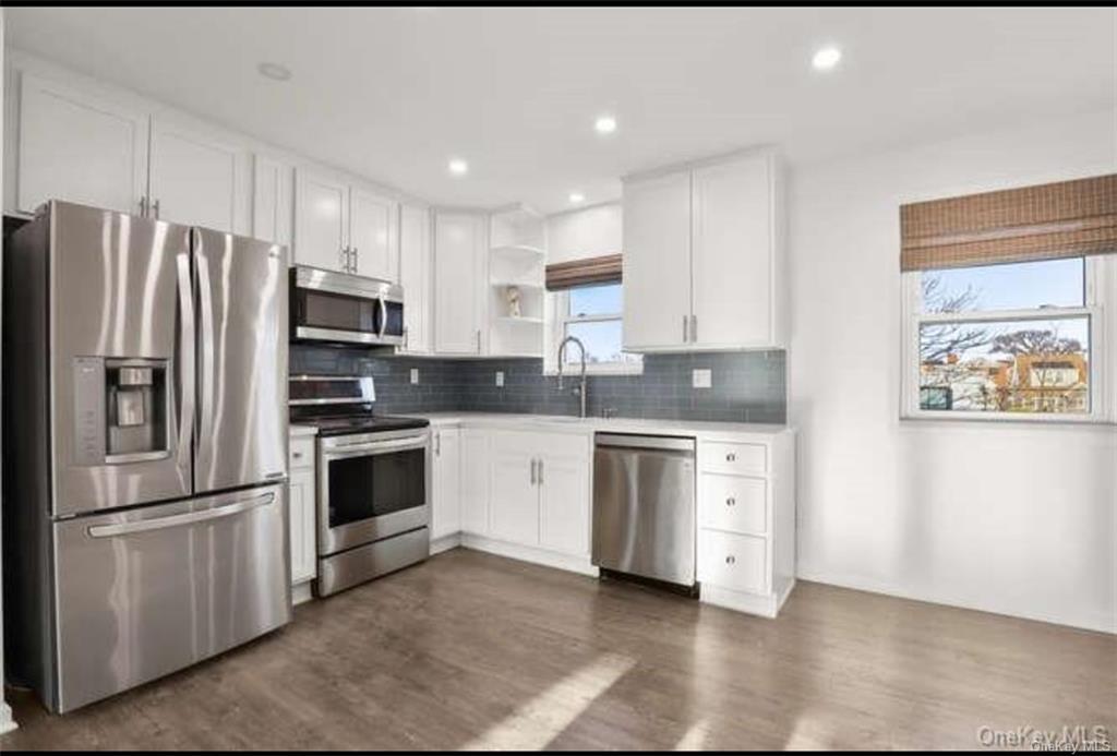 a kitchen with stainless steel appliances white cabinets and a refrigerator