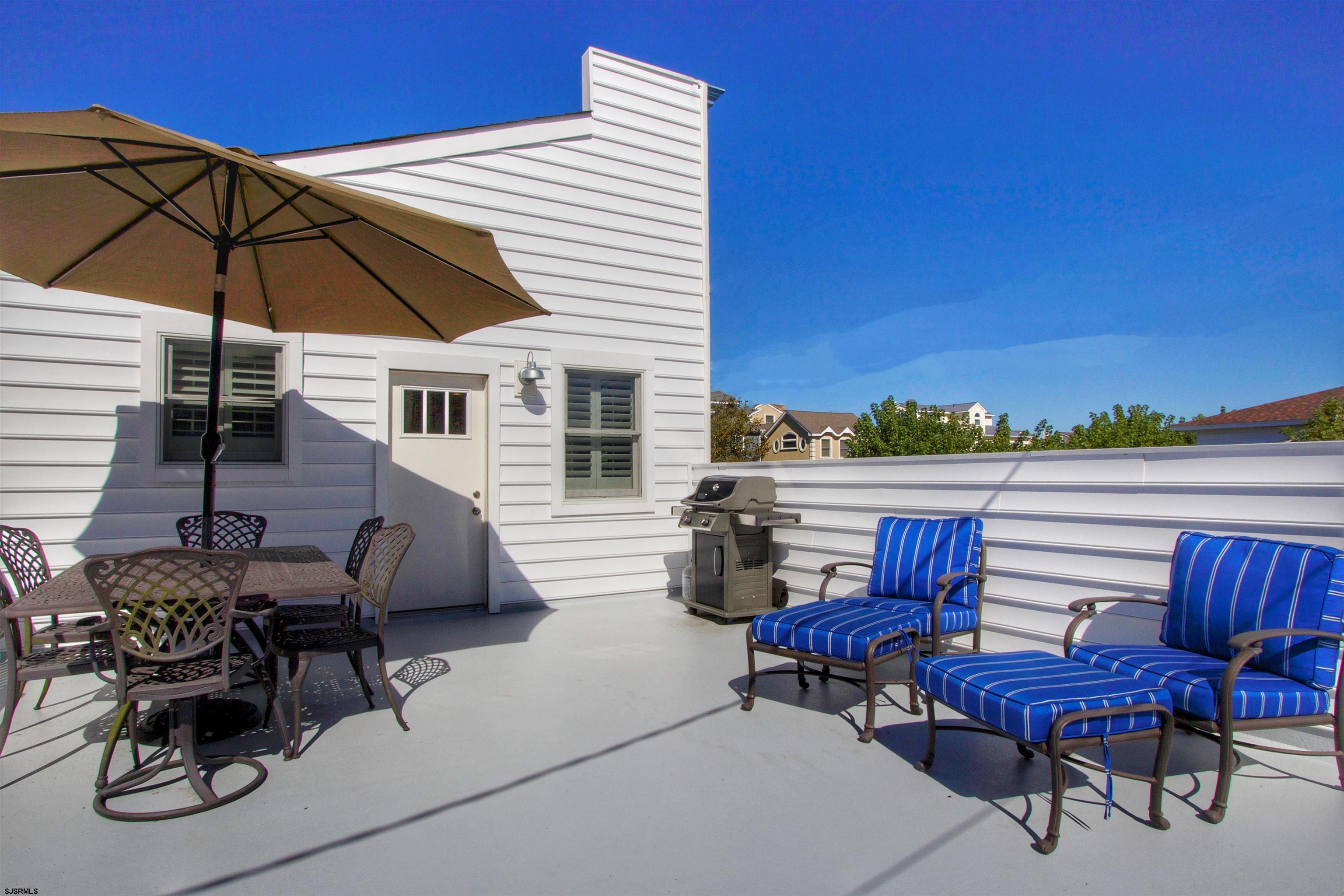 a view of a patio with couches table and chairs under an umbrella