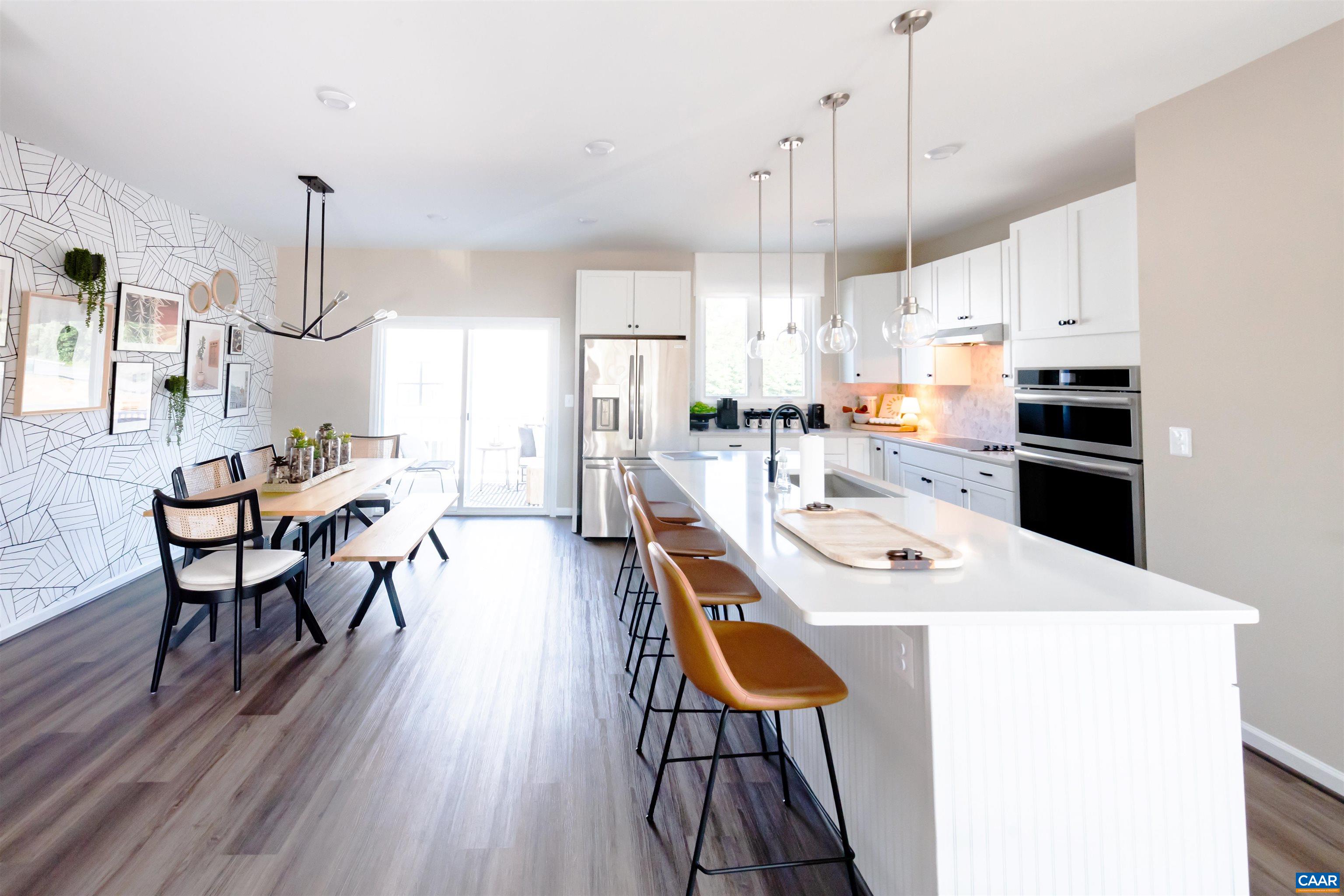 a kitchen with stainless steel appliances a table chairs stove and wooden floor