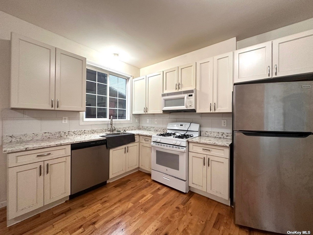 a kitchen with granite countertop white cabinets and white appliances