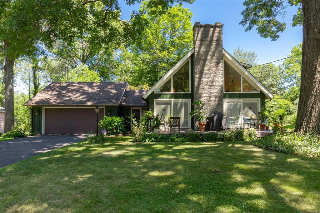 a view of a house with a big yard potted plants and large tree