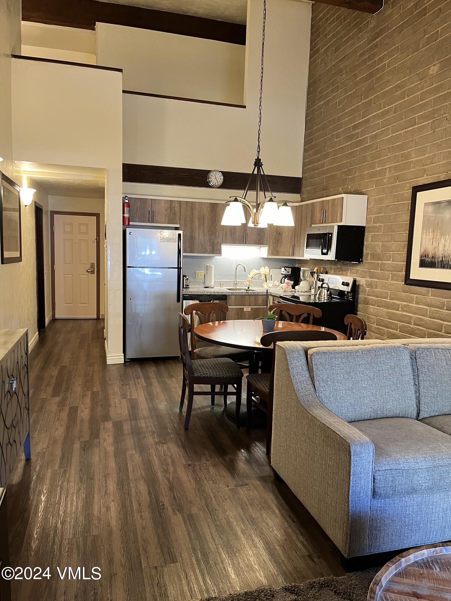 a living room with couches chairs and kitchen view with wooden floor