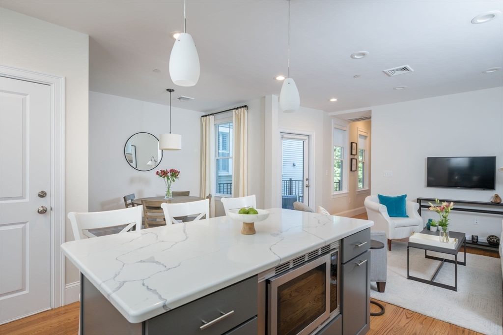 a view of kitchen island a sink wooden floor and living room view