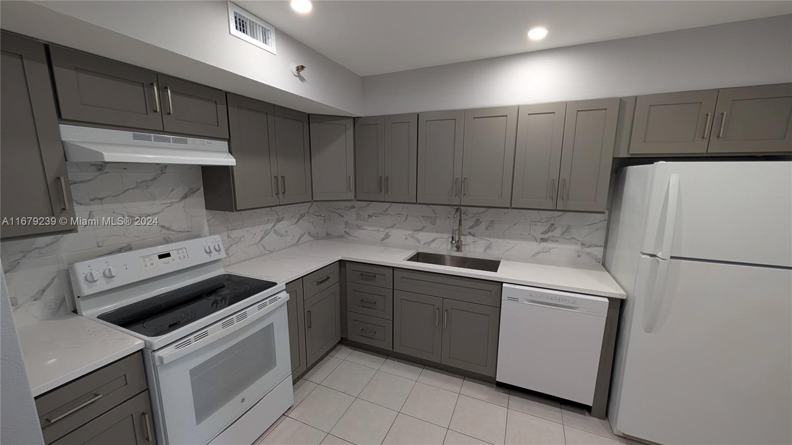 a kitchen with a sink a refrigerator and cabinets