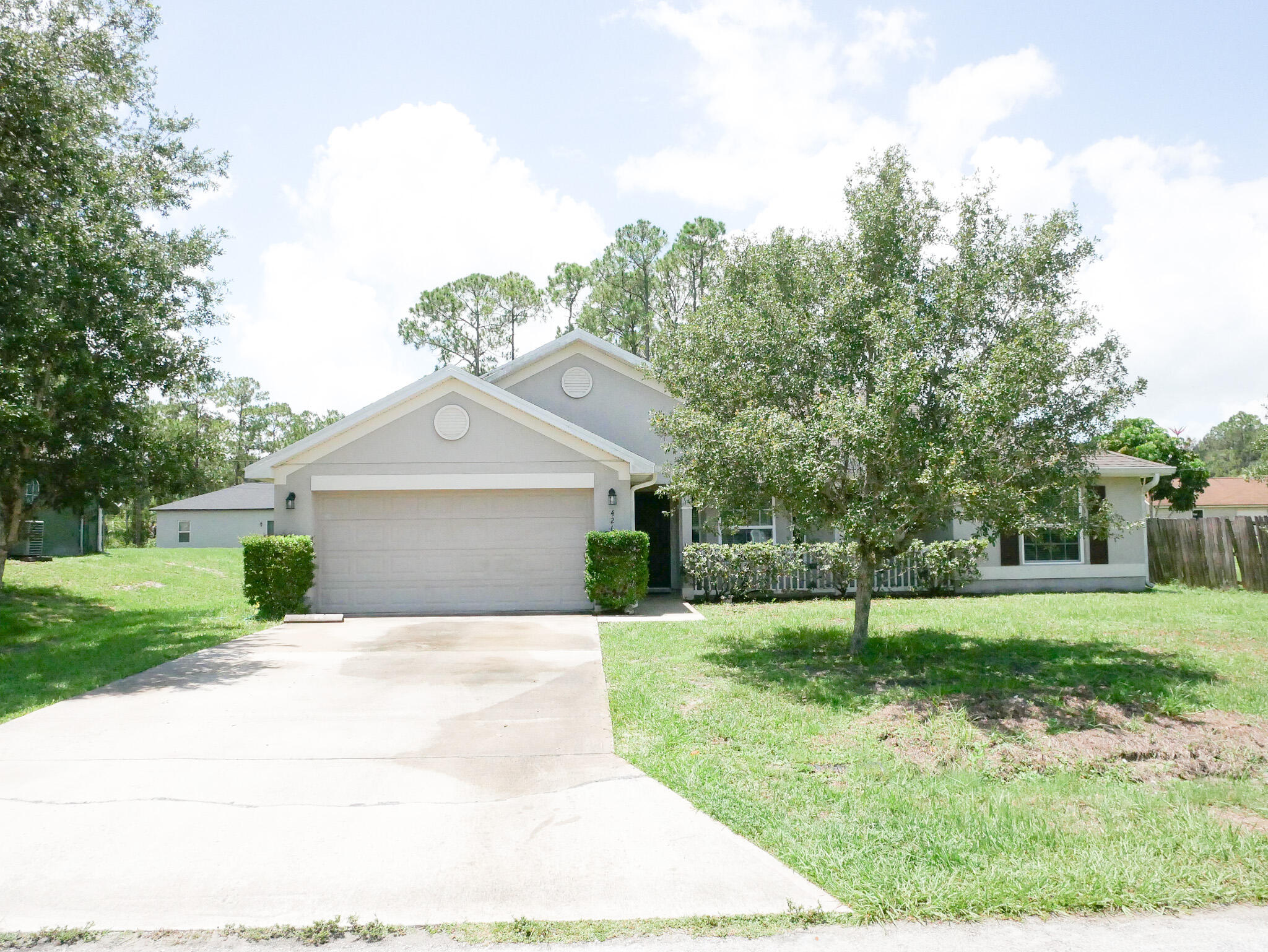 a view of a house with a yard and large trees