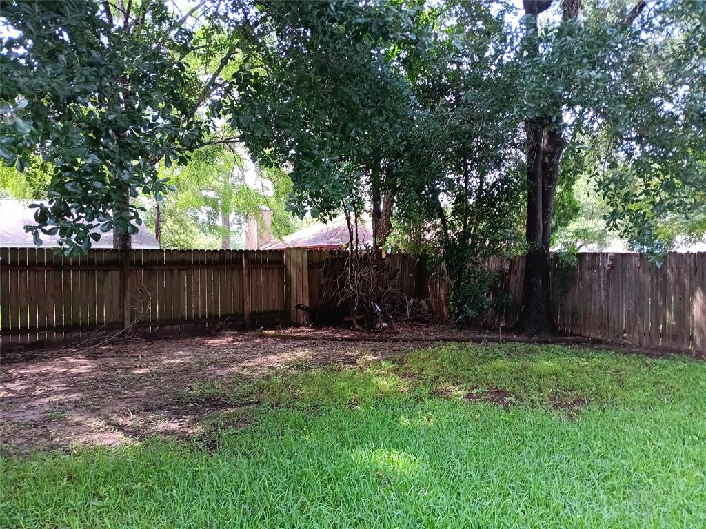 a view of a yard with wooden fence and a large tree