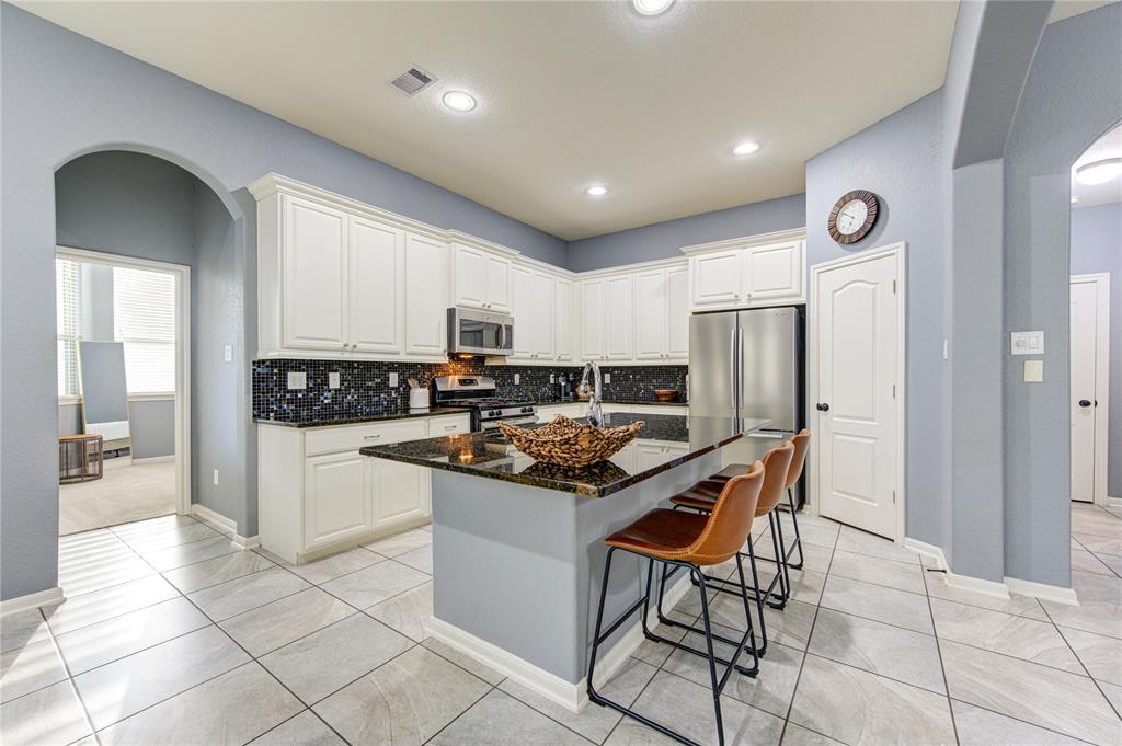 Step into the modern and stylish kitchen of 25123 Lakecrest Glen Dr, Katy, TX 77493. This beautifully designed kitchen features a large island with a breakfast bar, perfect for casual dining and entertaining. The kitchen is adorned with granite countertops, a sleek designer backsplash, stainless steel appliances, and soft-close cabinets. Under-cabinet lighting enhances the workspace, making cooking a delightful experience. The spacious and open layout seamlessly connects the kitchen to the living areas, ens