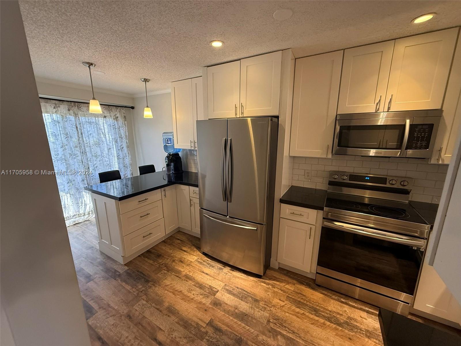 a kitchen with granite countertop a refrigerator stove and microwave