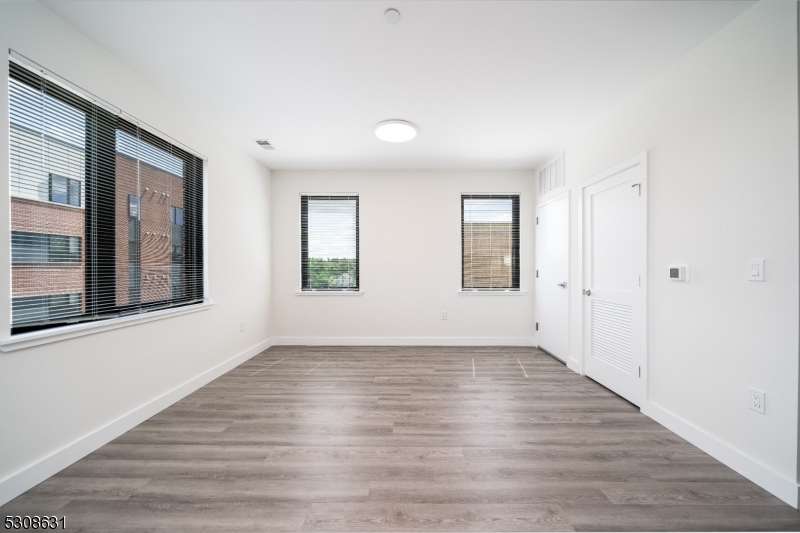 a view of an empty room with wooden floor and windows