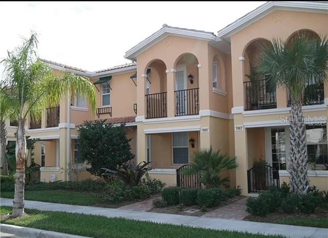 a view of a white house with a large windows and a yard with palm trees