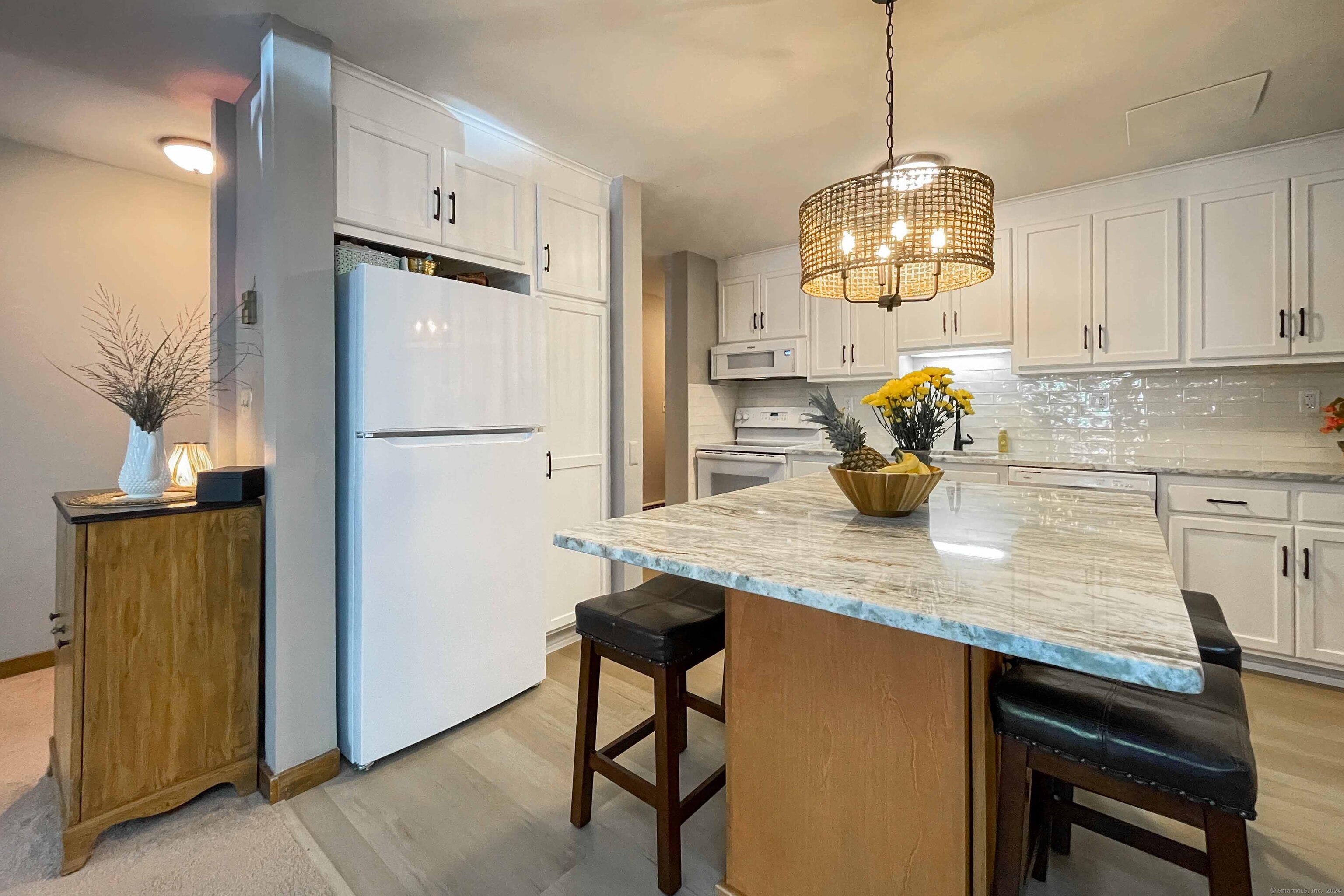 a kitchen with stainless steel appliances granite countertop a dining table chairs and cabinets