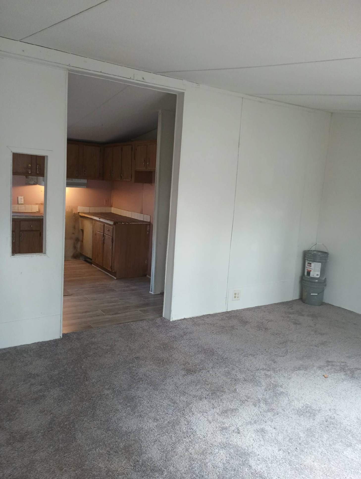 a view of an empty room and a kitchen