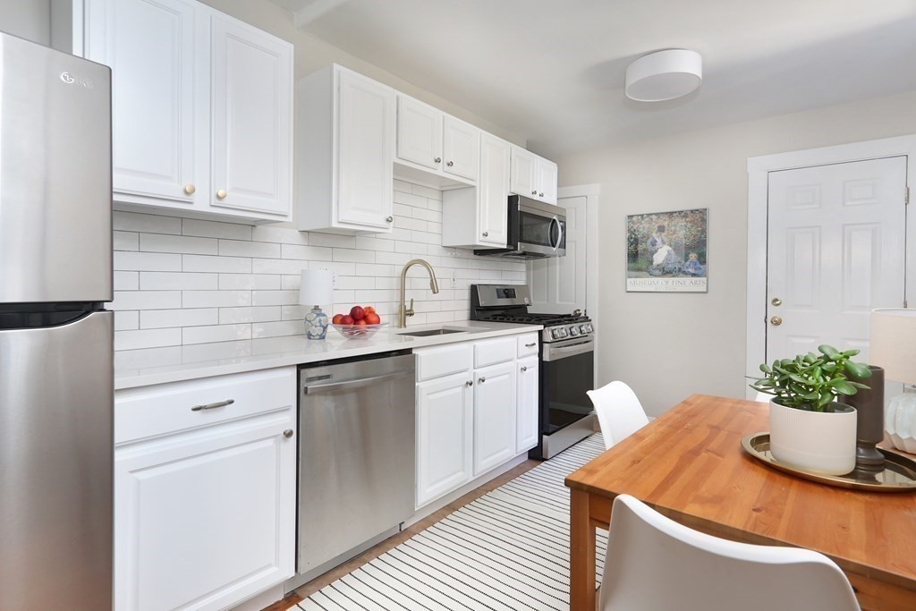 a kitchen with stainless steel appliances kitchen island granite countertop a refrigerator sink and white cabinets