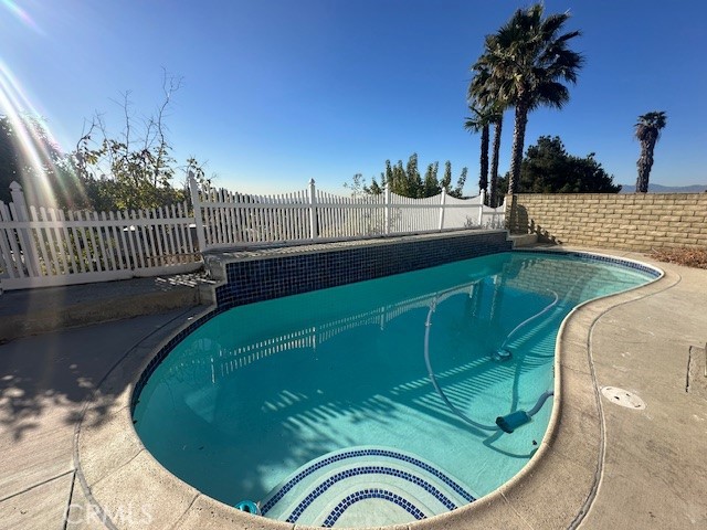 a view of a swimming pool with a plants and wooden fence