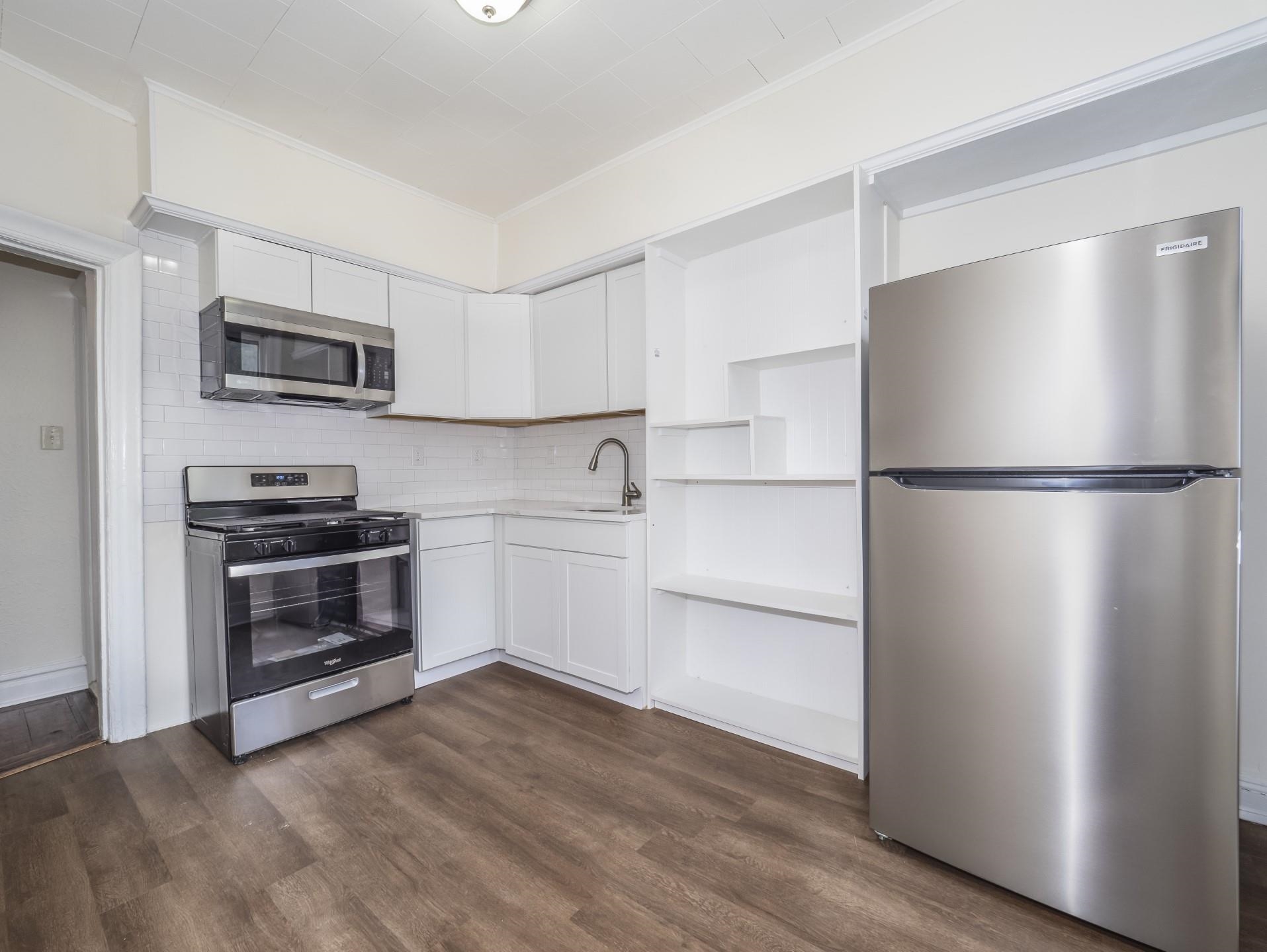 a kitchen with a refrigerator and a stove top oven