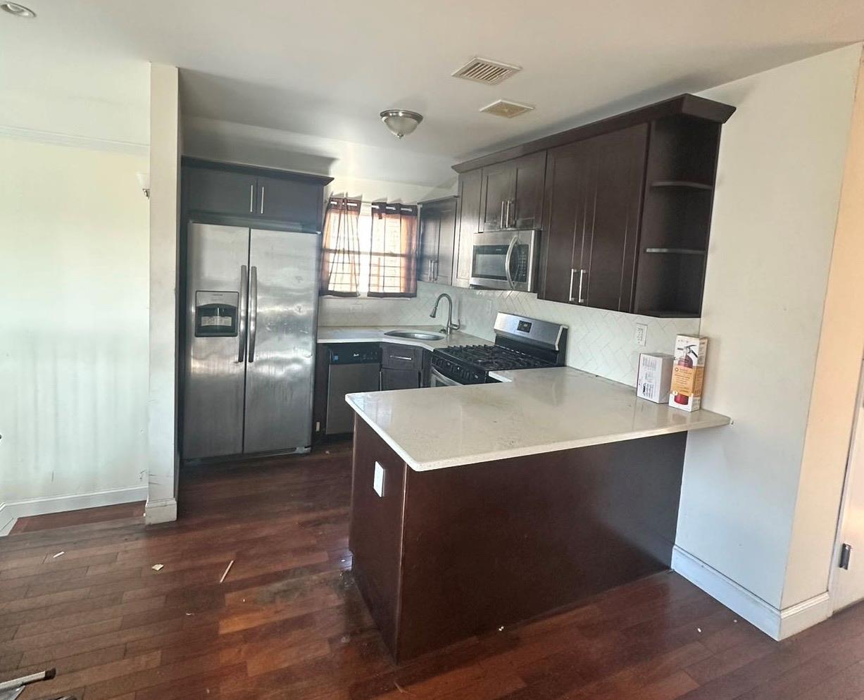 Kitchen with kitchen peninsula, sink, dark hardwood / wood-style flooring, and appliances with stainless steel finishes