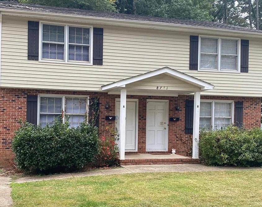 a view of a brick house with plants and windows