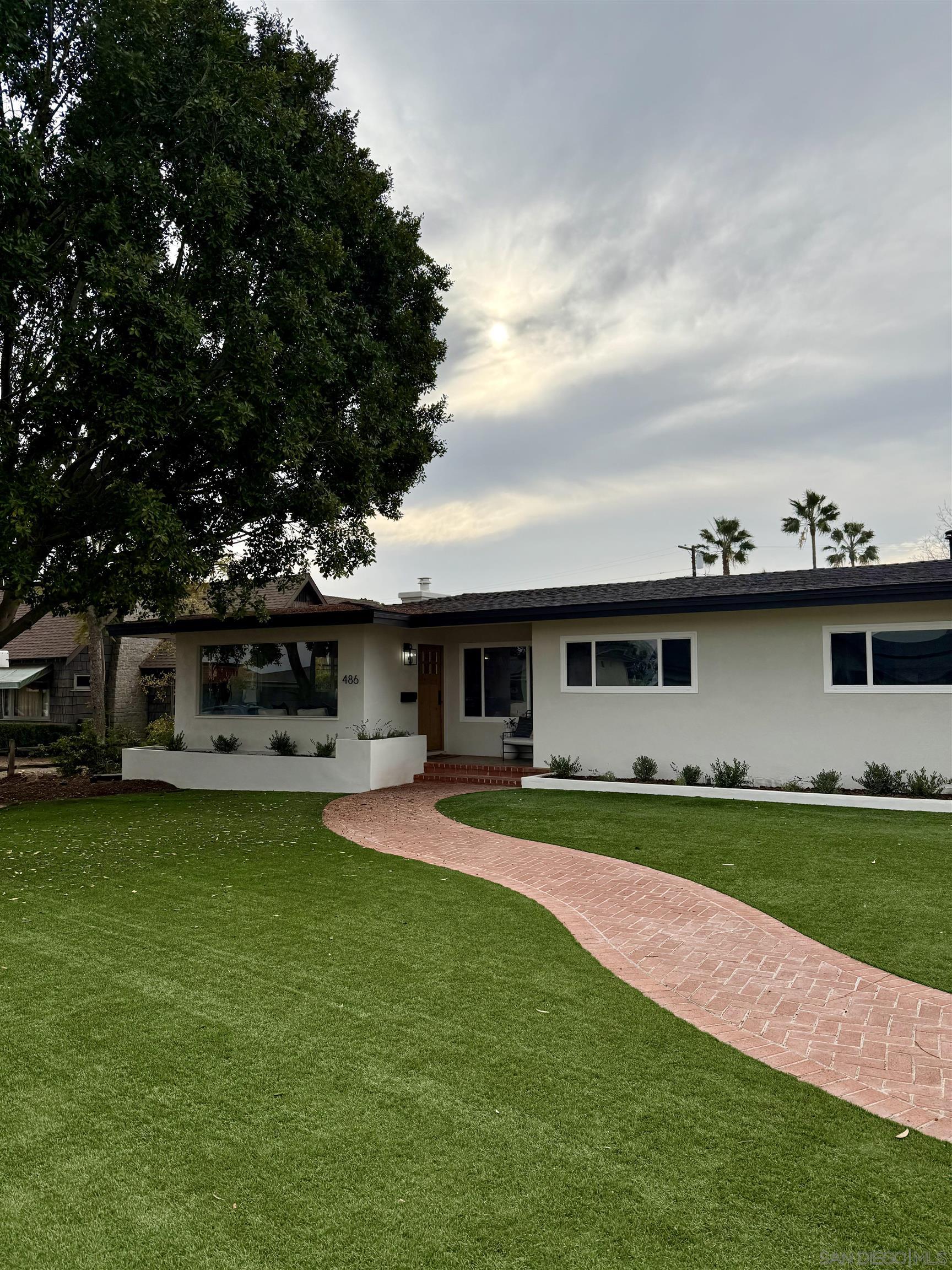 a front view of a house with a garden and trees