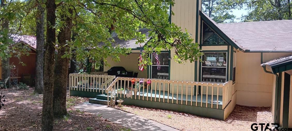 a view of a wooden house with a small yard and wooden deck