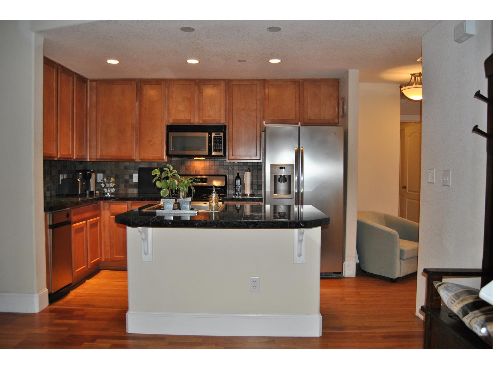 a kitchen with granite countertop a refrigerator and a stove top oven