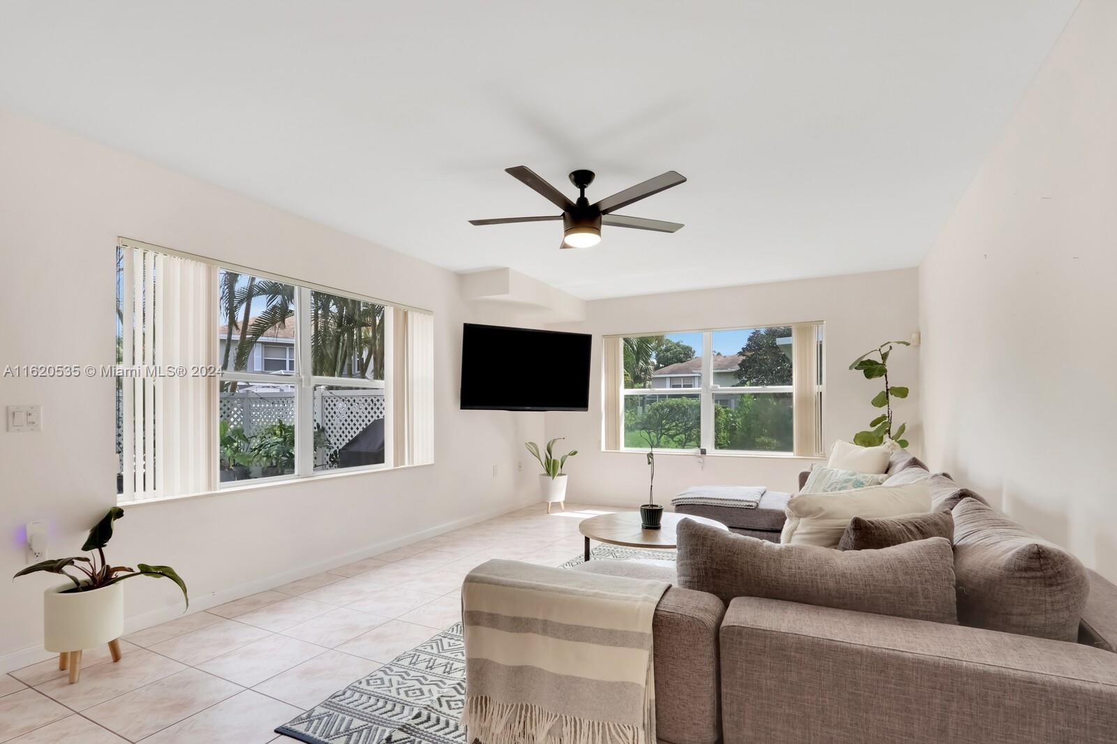 a living room with furniture a flat screen tv and a large window