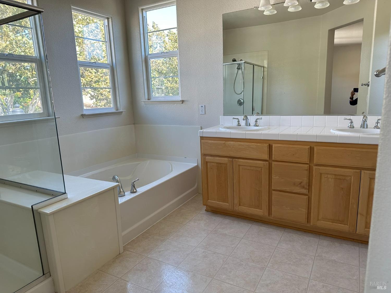 a spacious bathroom with a tub sink and mirror