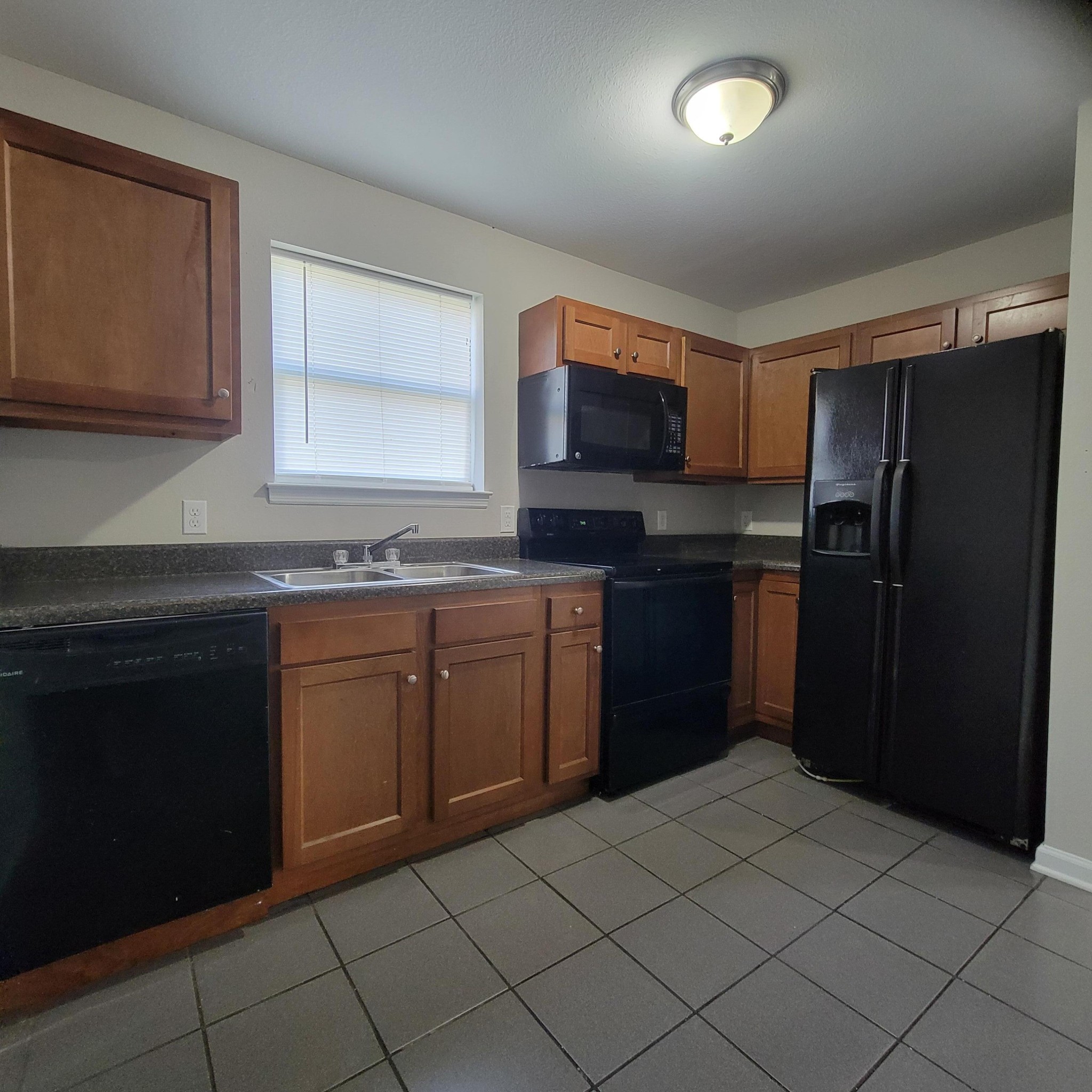 a kitchen with granite countertop a refrigerator and a stove top oven