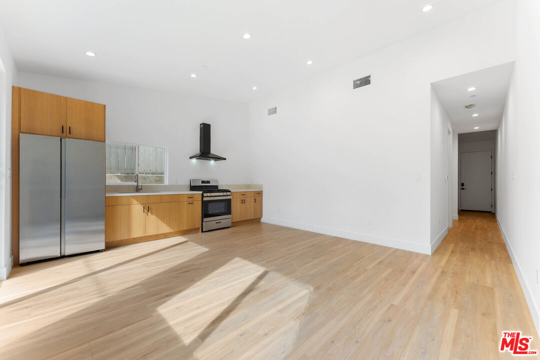 a kitchen with stainless steel appliances kitchen island a refrigerator sink and wooden floor